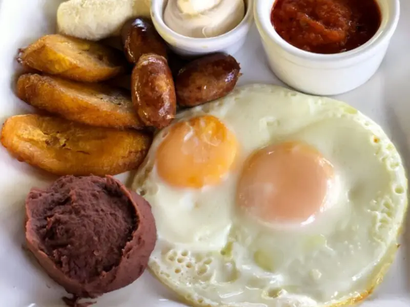 Salvadoran plate with fried plantains, egg, beans, cream and chorizo