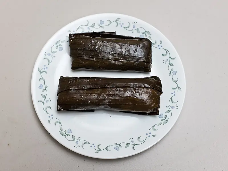 Two Salvadoran tamales wrapped in banana leaf